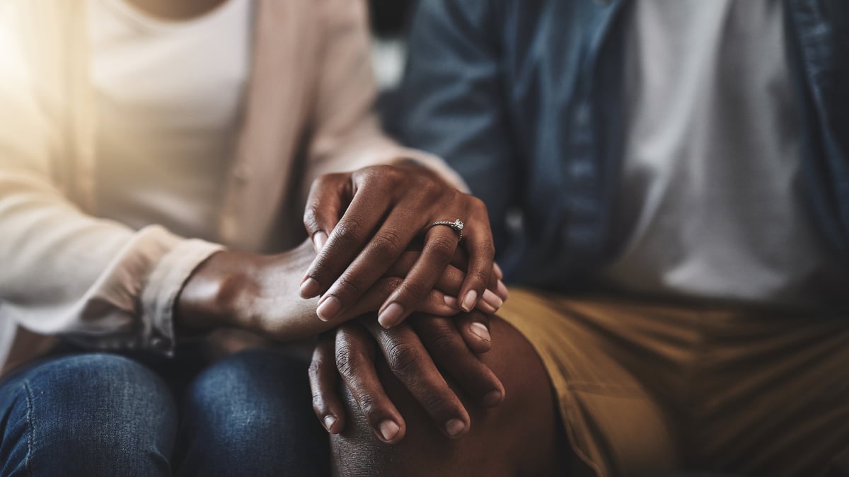 A married couple sitting together and holding hands