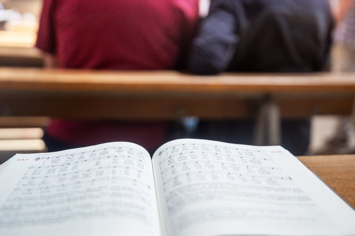 An open hymnal resting in a church pew