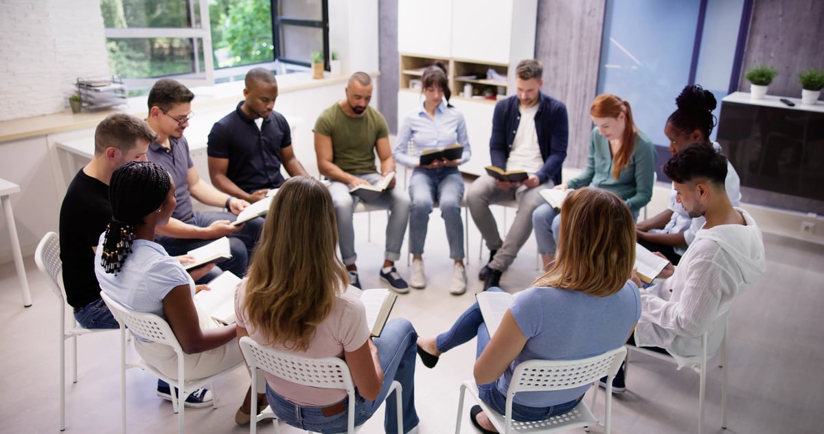 Diverse group of teens and adults reading and studying the Bible together