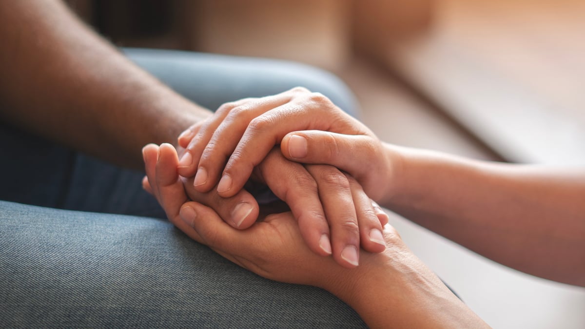 A couple holding hands in comfort and trust