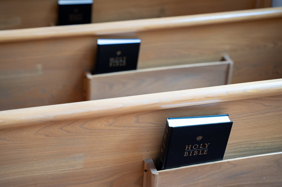 A Holy Bible resting on a wooden church pew