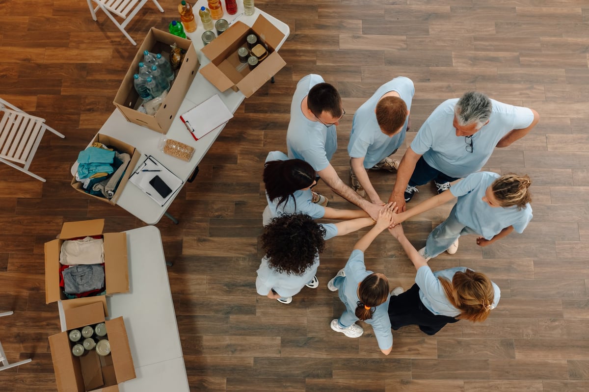 A diverse group joining hands together in service and giving