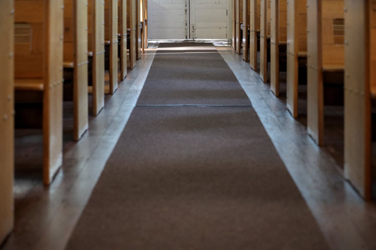 A quiet traditional church interior with wooden pews leading down the aisle