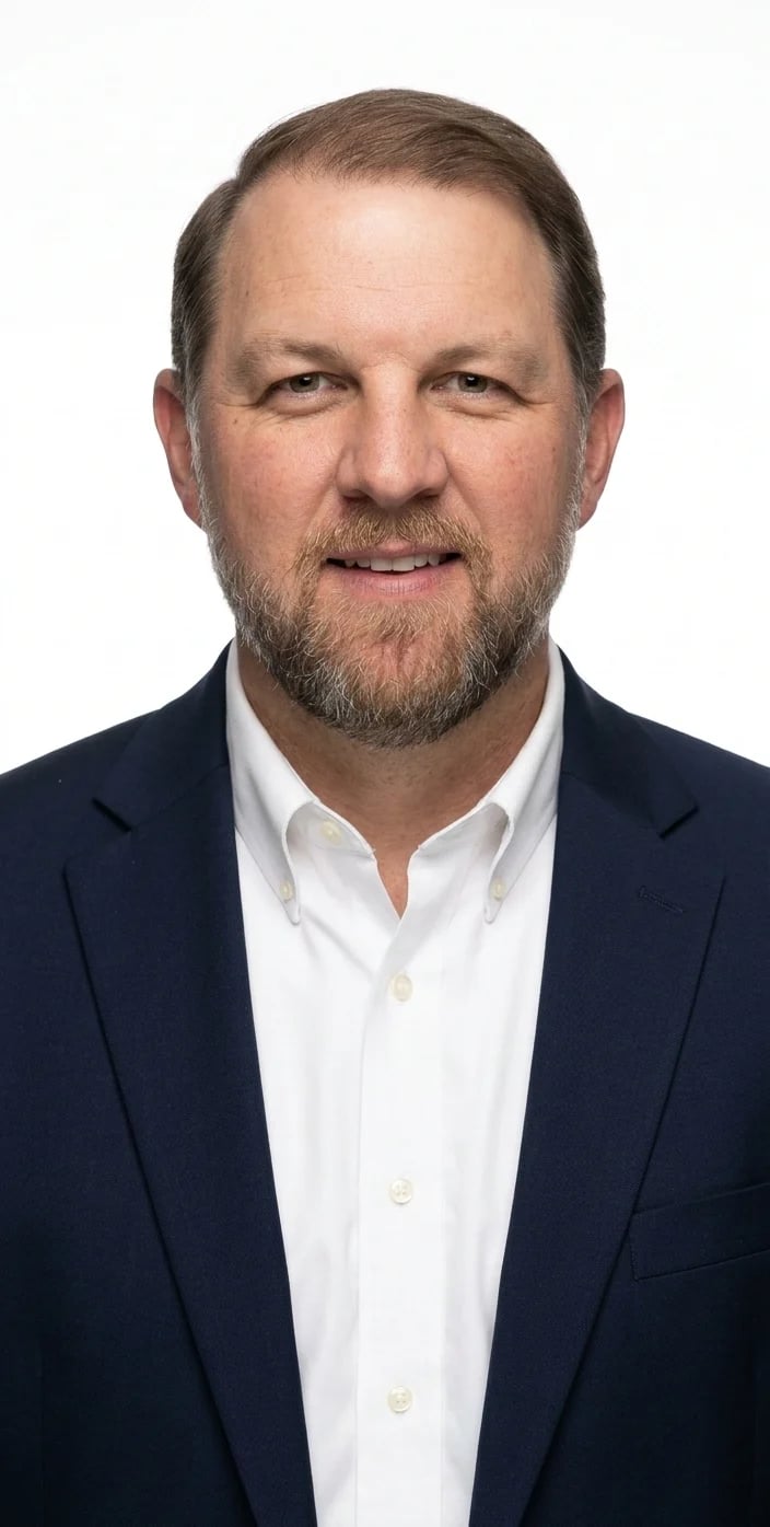 Professional headshot of Pastor Jason Kokenzie, a middle-aged man with brown hair and beard, wearing a dark blazer and white button-up shirt
